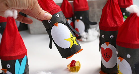 Hand nimmt Pinguin aus einem Adventskalender
